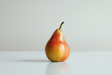 A single whole pear is placed on a clean white surface, with a plain white background. The pear is ripe and ready to be eaten.