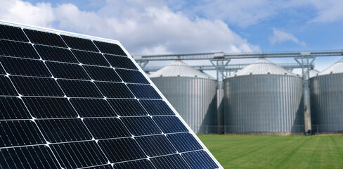 Modern farm using renewable energy. Solar panels with silos in the background