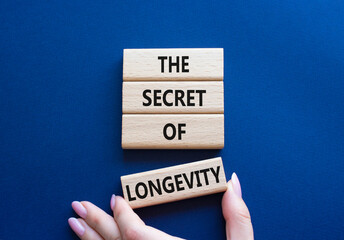 The Secret of Longevity symbol. Wooden blocks with words The Secret of Longevity. Beautiful deep blue background. Businessman hand. Business and The Secret of Longevity concept. Copy space.