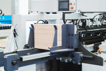 A machine is cutting wooden Chipboard into small pieces