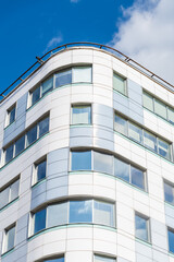 Side view of white and blue glass wall of modern office or residential building in a sunny day. Copy space. Clear blue sky. Soft focus. Housing development real estate development theme.	