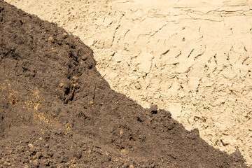 A close-up photo of the surface of two different types of soil. One soil is a dark brown, while the other is a lighter brown. The soil surface is rough and textured
