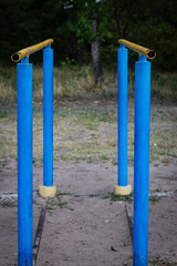 Fototapeta premium Vertical color photo, sports equipment, iron bars for pulling up, exercise equipment for a healthy lifestyle, on a sunny day on the coast among trees. An outdoor exercise area.