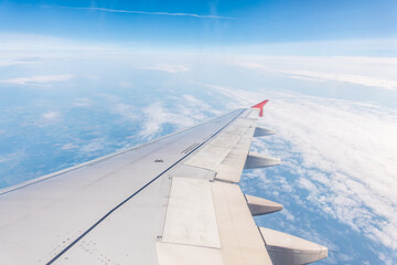 Fototapeta premium View from the airplane window at a beautiful cloudy sky and the airplane wing