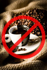 Coffee cup and coffee beans on canvas with warning crossed out sign. Concept of coffee risk