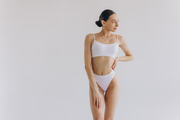 Fototapeta premium Portrait of beautiful woman with slim body in underwear posing in the white studio background with copy space, mock-up