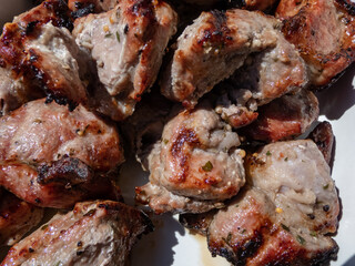 Macro of meat cooked on metal skewers - juicy pork grilled on fire, coals and smoke in grill. Seasoned cubes of meat