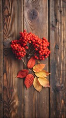 Autumn leaves and rowan berries on a brown wooden background.
