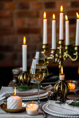 Rustic elegant table decor for christmas family dinner. Center piece with white candle, pine cone, fir tree branches. Zero waste eco-friendly home decoration. Cozy atmosphere, wooden background.