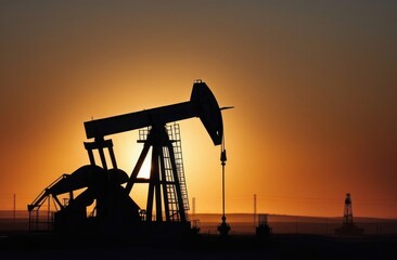 Oil production station in silhouette at sunset.