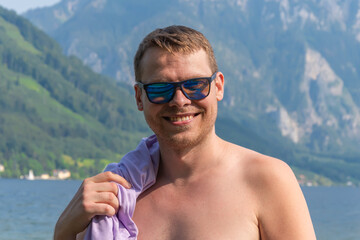 Portrait of a man of 40-45 years old in sunglasses on the background of mountains and water.