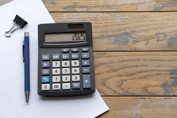 Calculator with the number 2025 on the display and stationery. Concept of finance, taxes, savings...