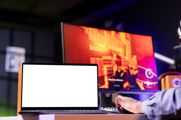 Mockup laptop display next to player using keyboard to play FPS videogame, shooting enemies. Isolated screen notebook near person gaming on computer desktop at home, close up shot