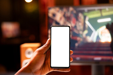 Focus on isolated screen cellphone held by gamer playing singleplayer videogame on gaming PC...