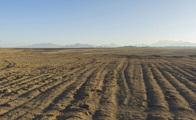 High angle and afternoon view of sand and dirt againt land horizon and mountain at Sahara Desert, Hurghada, Egypt
