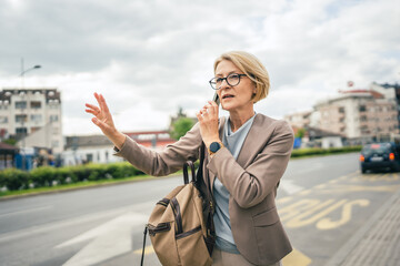 mature woman stand at city bus stop use smartphone while wait drive