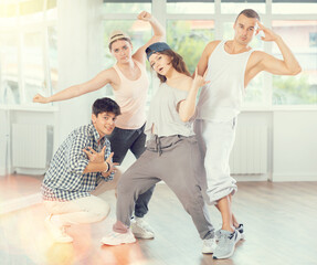 Active girls and guys posing collectively demonstrating breakdance moves in training hall