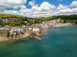 a coastal village with houses on cliffs and a clear blue sea in Cornwall, England