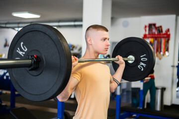 Strong and young bodybuilder lifting weights during a workout in a gym. 