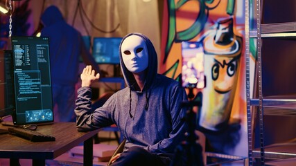 Masked hackers filming ransom video in hidden underground base, threatening to release stolen data publicly if payout demands are not met. Rogue programmers using phone to record blackmail footage