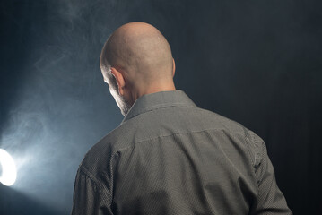 Bald middle-aged man with his back to the camera.