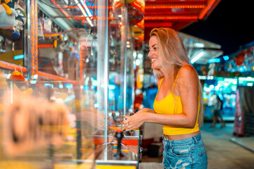 Obraz premium Woman having fun playing arcade games at fair at night