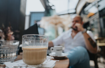 Businessman enjoying coffee at a modern outdoor cafe, reflecting during a casual meeting or work break. Perfect for themes of relaxation, work-life balance, and contemporary lifestyle.