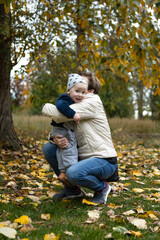 Fototapeta premium Young mother and her little son having fun in the autumn park.