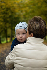 Young mother and her little son having fun in the autumn park.