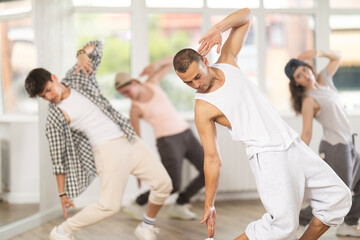 During hip hop dance lesson, guy leads, conducts classes, teaches students to correctly perform elements and sequence of movements