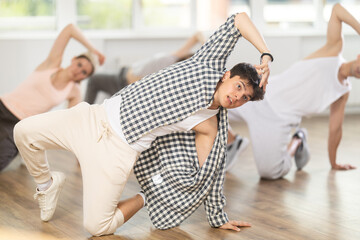 Man conducts training course for aspiring hip hop and break dance dancers. Band performs elements almost lying down, crouching to floor, in pose of inverted bridge.