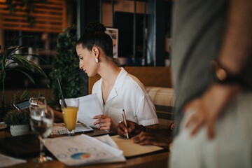 Businesspeople collaborating during a meeting in a coffee bar, reviewing documents and engaging in productive discussion.