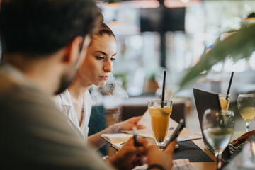 Focused businesspeople discussing work during a meeting at a coffee bar, with drinks and a laptop on the table.
