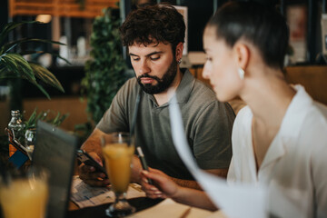 Two businesspeople having a meeting at a coffee bar, discussing documents and using technology.