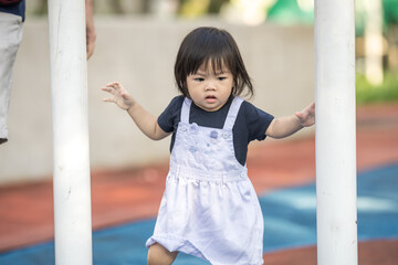 Obraz premium A one-year-old Chinese Malaysian girl playing on the children's playground equipment at KLCC Park in Kuala Lumpur City Centre, Malaysia.