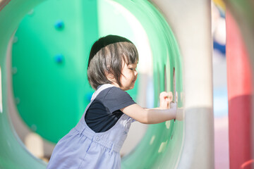 A one-year-old Chinese Malaysian girl playing on the children's playground equipment at KLCC Park in Kuala Lumpur City Centre, Malaysia.