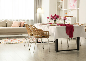 Beautiful table setting with flowers and rattan chairs in dining room