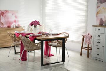Pink peonies on table with beautiful setting and rattan chairs in dining room