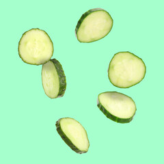 Fresh cucumber slices in air on turquoise background