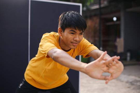 Young Asian Sportsman Stretching Arms With Pushing Hands Outdoor