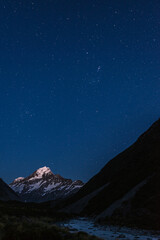 Mount Cook viewed from Hooker valley at night under a clear starlit night, with the constellation Orion prominent. Mt Cook Aoraki National Park, New Zealand.