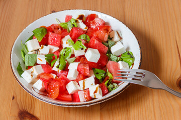 Fresh summer salad with watermelon, tomato, feta cheese and basil on wooden table