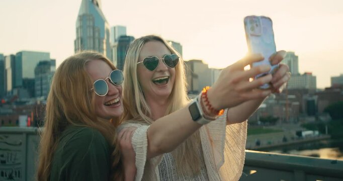 Two young female tourists smile and take selfies in downtown Nashville