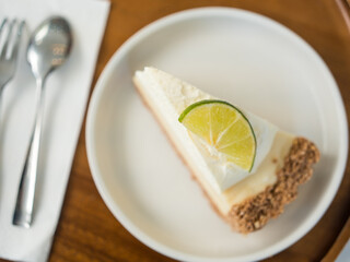 Slice of lemon cheesecake on white dish.