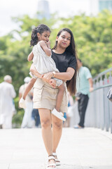 A 30-something Indian Malaysian mother wearing a miniskirt and her 5-year-old daughter in a white dress spending time joyfully on a bridge in City Centre, Kuala Lumpur, Malaysia.