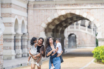 Two 30-something Indian Malaysian mothers with their 7-year-old son and 5-year-old daughter walking...