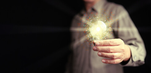 Idea and solution for business and technology. A man holds a glowing lightbulb with network and...