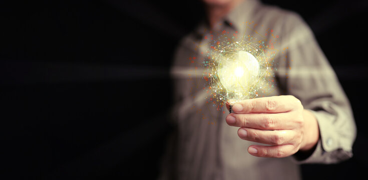 Idea and solution for business and technology. A man holds a glowing lightbulb with network and many digital gear icons around it