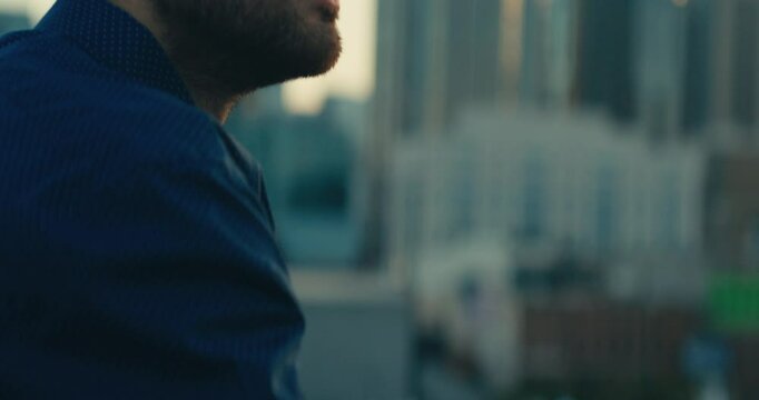 Young man standing on a bridge looking out at the sunset