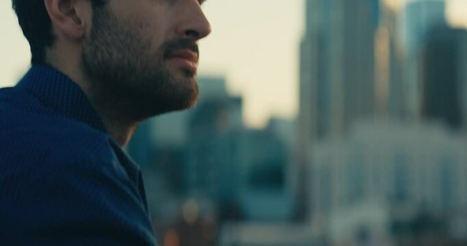 Young man standing on a bridge looking out at the sunset